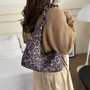 Large leopard print hobo shoulder bag with pleated strap on a model in home setting