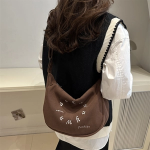 Sac bandoulière en velours côtelé marron avec broderie porté par un mannequin en scène