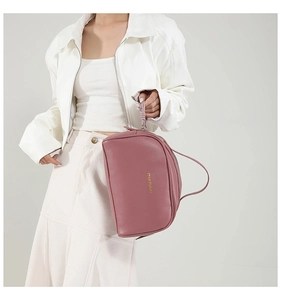 Close-up of pink PU leather makeup bag with litchi texture and gold logo details