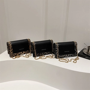 Three fashion leopard print crossbody square bags with gold chains on white podium