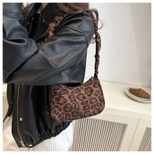 Dettaglio macro del tessuto leopardato e della tracolla a pieghe di una borsa hobo