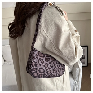 Borsa baguette viola leopardata indossata con un elegante trench beige