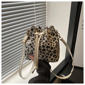 Detailed close-up of leopard print drawstring bucket bag with cream shoulder strap