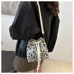Detail shot of leopard print bucket bag with drawstring closure and golden hardware