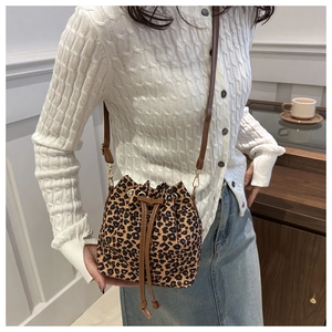 Chic leopard print drawstring bucket bag worn by model in a cozy indoor setting