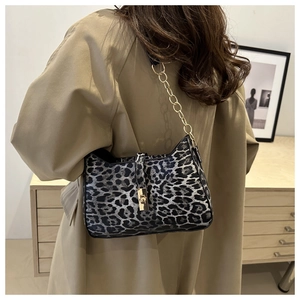 Gros plan du sac porté épaule léopard avec chaîne dorée sur une tenue de trench-coat