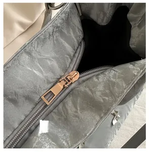 Detail of a smooth golden metal zipper on a grey textured large-capacity shoulder bag