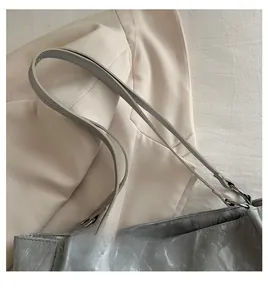 Detail of silver pleated handbag showing leather straps and metal ring hardware