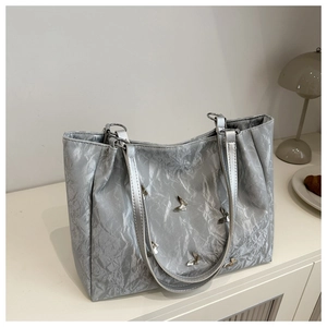 Detailed shot of silver tote bag with metallic crinkle texture and butterfly charms