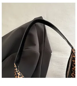 Detail of minimalist black shoulder bag featuring stylish leopard print wide strap