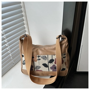 Close-up of jacquard floral stitching and wide woven strap on a khaki tote bag