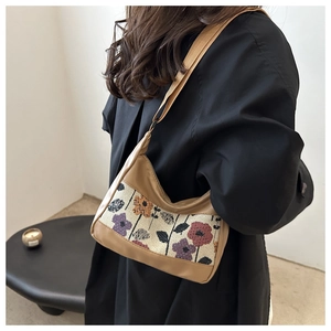 Detail of vintage floral tapestry hobo bag with khaki trim worn over a black coat