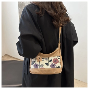 Detail of vintage crossbody bag with floral tapestry panel on a black coat outfit