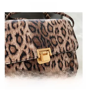 Close-up of leopard print shoulder bag with a gold rectangular metal flip lock closure