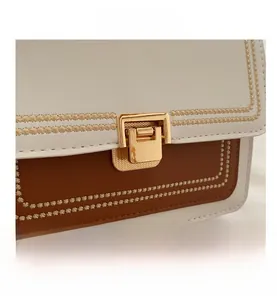 Close-up of color-block crossbody bag featuring contrast stitching and golden clasp
