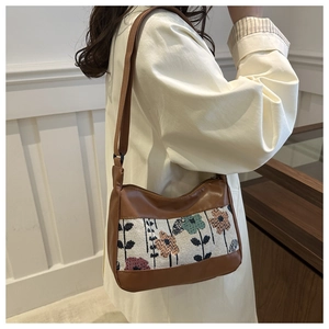 Detail of vintage canvas shoulder bag with floral embroidery and brown PU leather trim