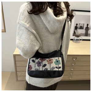 Detail of vintage canvas shoulder bag with colorful floral embroidery on leather