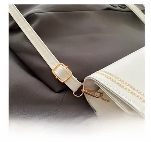 Detail of white leather shoulder bag with adjustable gold-tone buckle and metal hardware