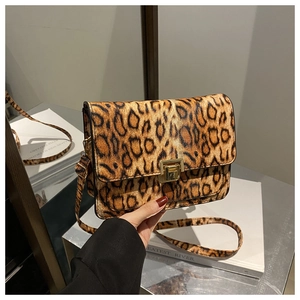 Detail of leopard print crossbody bag featuring a golden square buckle and textured leather