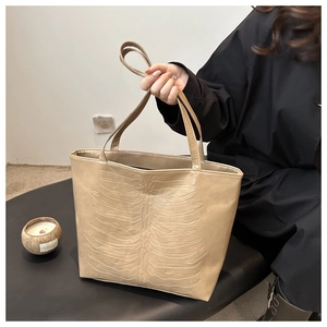 Detailed view of beige tote bag featuring 3D ribcage bone embossing on soft PU leather