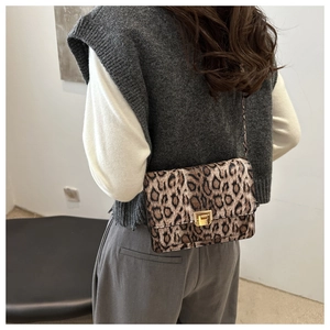 Detailed close-up of a leopard print crossbody bag featuring a golden metallic twist lock