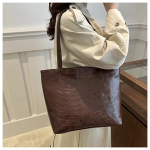 Detail of deep brown tote bag featuring unique 3D rib bone embossed pattern texture