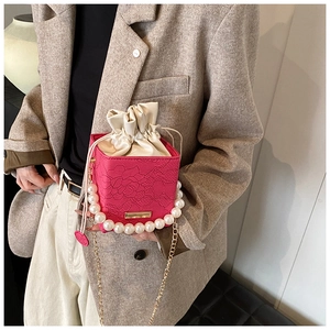Detail of rose pink box bag featuring 3D rose embossing, pearl handle and gold chain strap