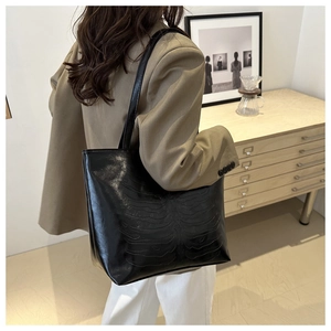 Large black tote bag with unique 3D rib bone embossed pattern worn by a model
