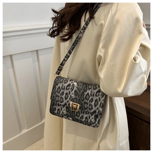 Detail of leopard print crossbody bag with gold buckle on a beige trench coat