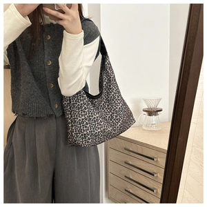 Detail view of a large leopard print hobo bag with black leather trim and shoulder strap