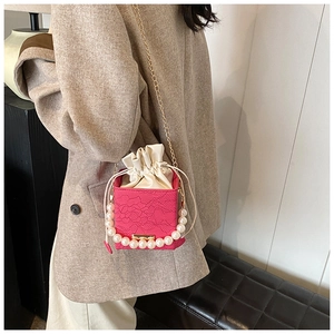 Details einer rosaroten Spitzen-Eimertasche mit Perlenobergriff und goldener Kette