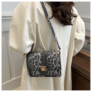 Détail du sac bandoulière à motif léopard avec fermoir porté sur un trench beige