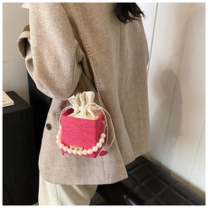 Close-up of rose red lace cube bag with large pearl handle and metal chain strap