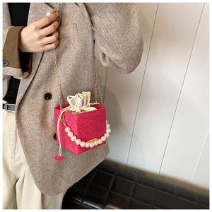 Detail der rosapinken Beuteltasche mit Perlengriff und floraler Texturstruktur