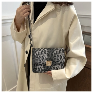 Chic leopard print crossbody bag with gold buckle on a model wearing an ivory coat