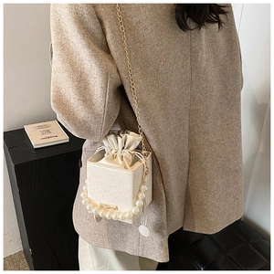Detail der weißen Spitzen-Box-Tasche mit Perlen Griff und goldener Kettenriemen