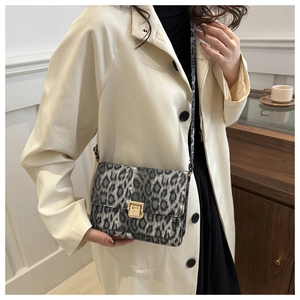 Detail of leopard print crossbody bag with vintage gold square buckle on a model