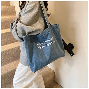 Macro detail of high-quality denim tote bag with Less Mondays More Sundays embroidery