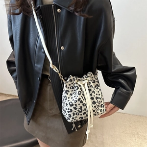 Chic leopard print drawstring bucket bag with white shoulder strap and gold hardware