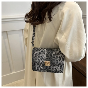 Detail of grey leopard print crossbody bag with golden clasp and adjustable strap
