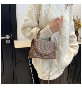 Close-up of vintage brown leather handbag with sparkling rhinestone flap and silver chain