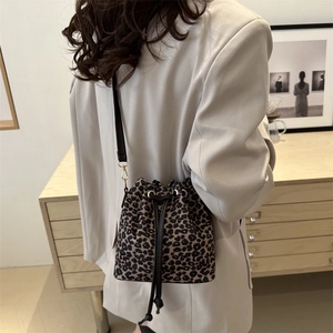 Chic leopard print drawstring bucket bag with gold hardware and slim leather strap