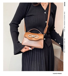 Close-up of brown crossbody bag featuring a rhinestone bow and adjustable shoulder strap