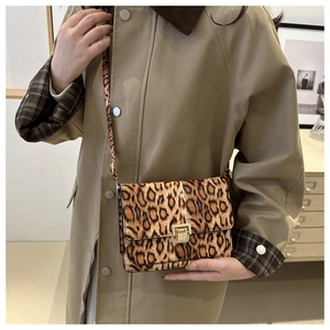 Détail du sac bandoulière léopard avec fermoir doré porté avec un trench-coat de couleur kaki
