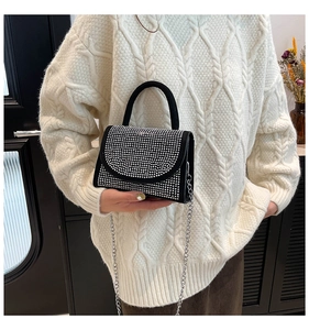 Close-up of a black handbag with sparkling silver rhinestones and a metal chain strap