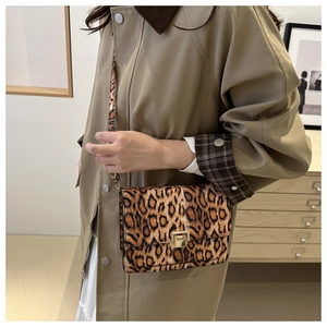Detail of leopard print crossbody bag with gold metallic buckle on a khaki trench coat