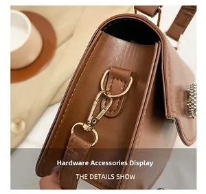 Detail of golden metal hooks and D-ring on brown leather bag with crystal buckle