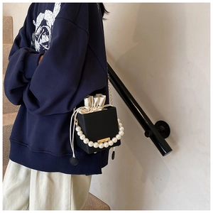 Detailansicht einer schwarzen Box-Bag mit Perlengriff und Kordelzug-Innenfutter aus Seide