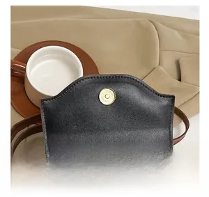 Detail of a brown leather shoulder bag featuring a gold magnetic closure and fine stitching