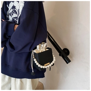 Detail of square bucket bag with large pearl handle and golden chain strap for women